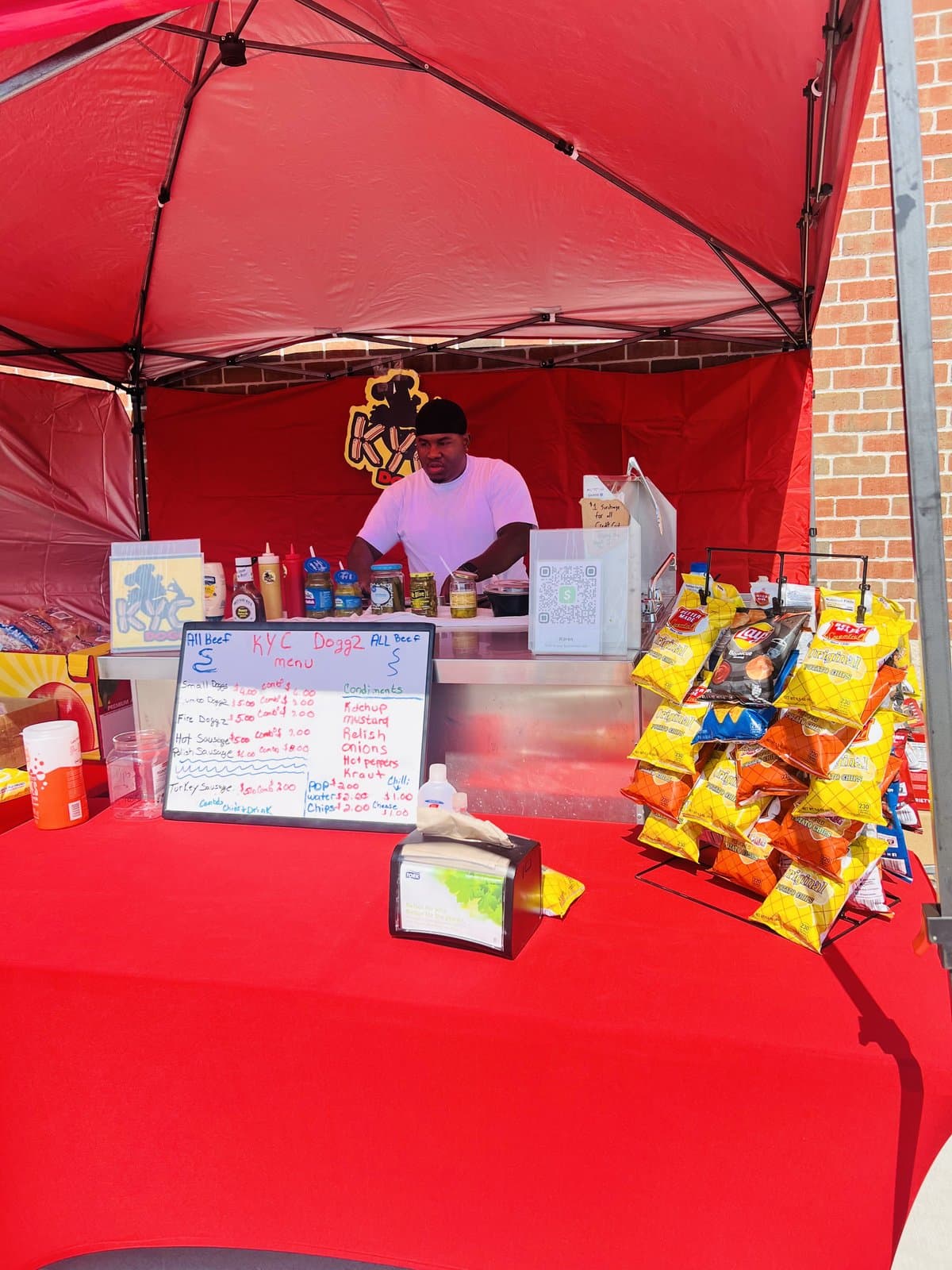 Mr. Cannady working the cart under the red tent with menu board and chips