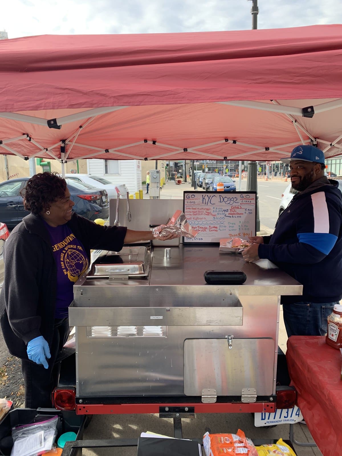 Karen serving a customer at the KYC Doggz cart downtown